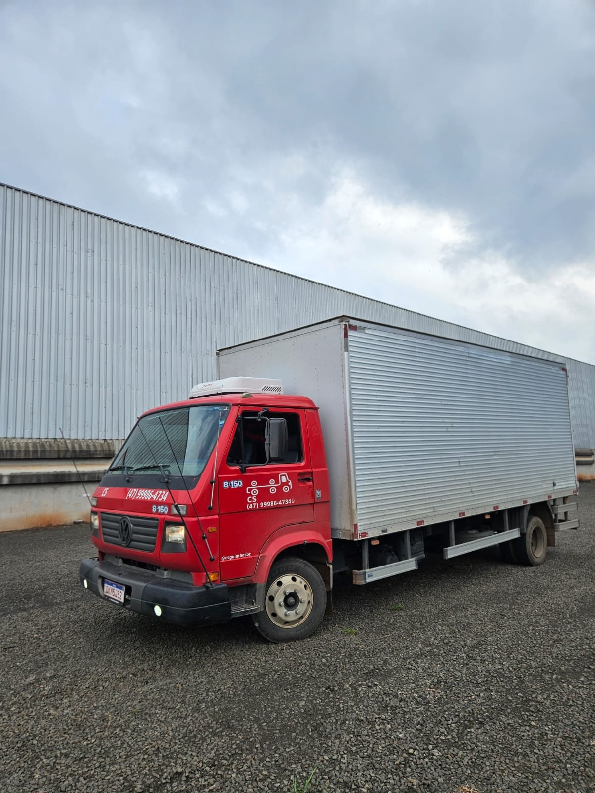 Caminhão baú da CS Transportadora estacionado ao lado do galpão de carga