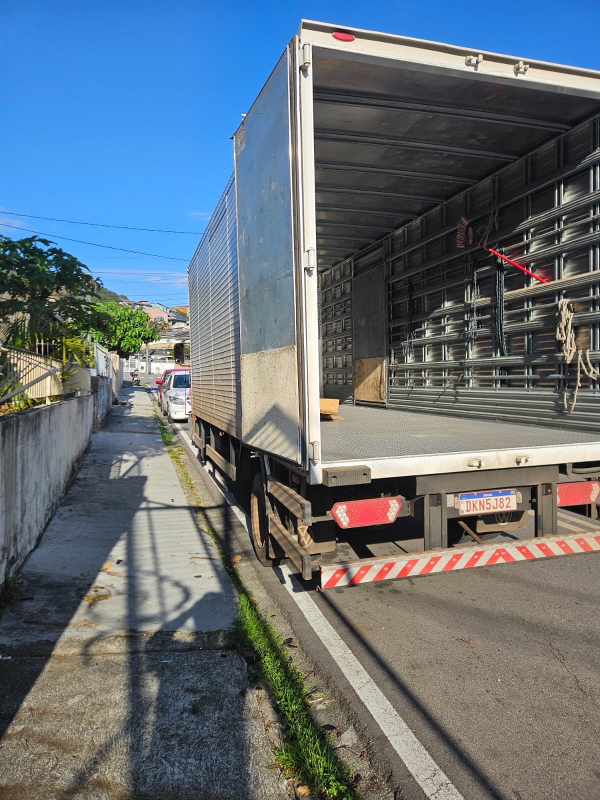 Caminhão baú da CS Transportadora com o baú aberto durante uma entrega na rua