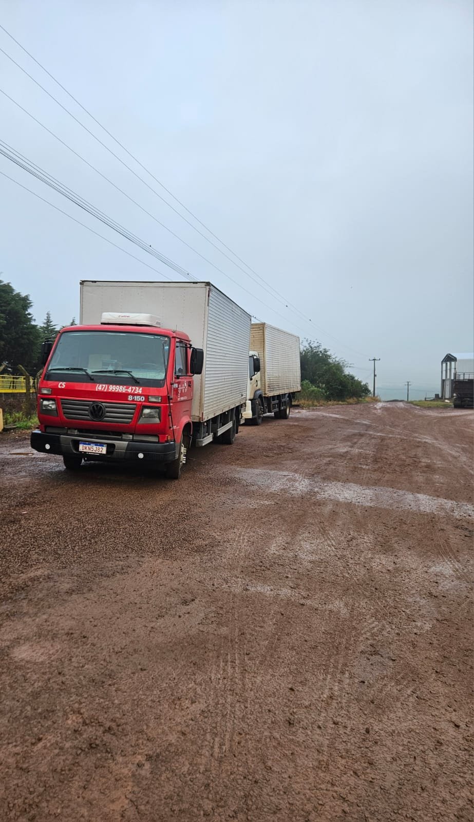 Caminhões da CS Transportadora em estrada de chão sob chuva, a caminho da entrega