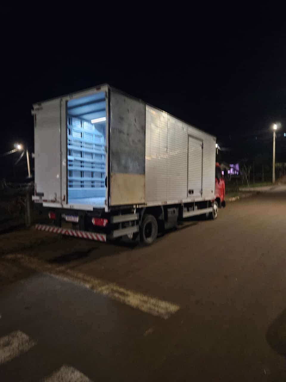Caminhão baú da CS Transportadora carregado com paletes durante entrega noturna