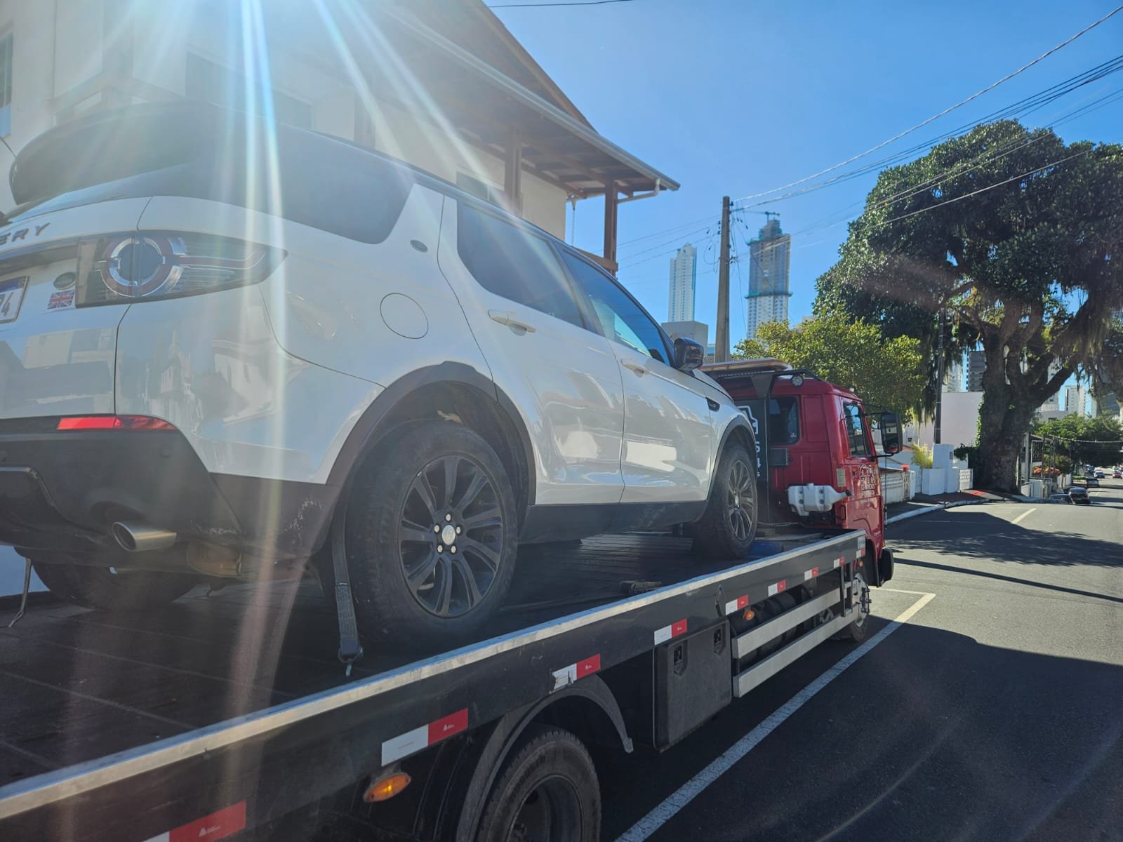 Guincho da CS Transportadora rebocando uma Land Rover com o skyline de Balneário Camboriú ao fundo