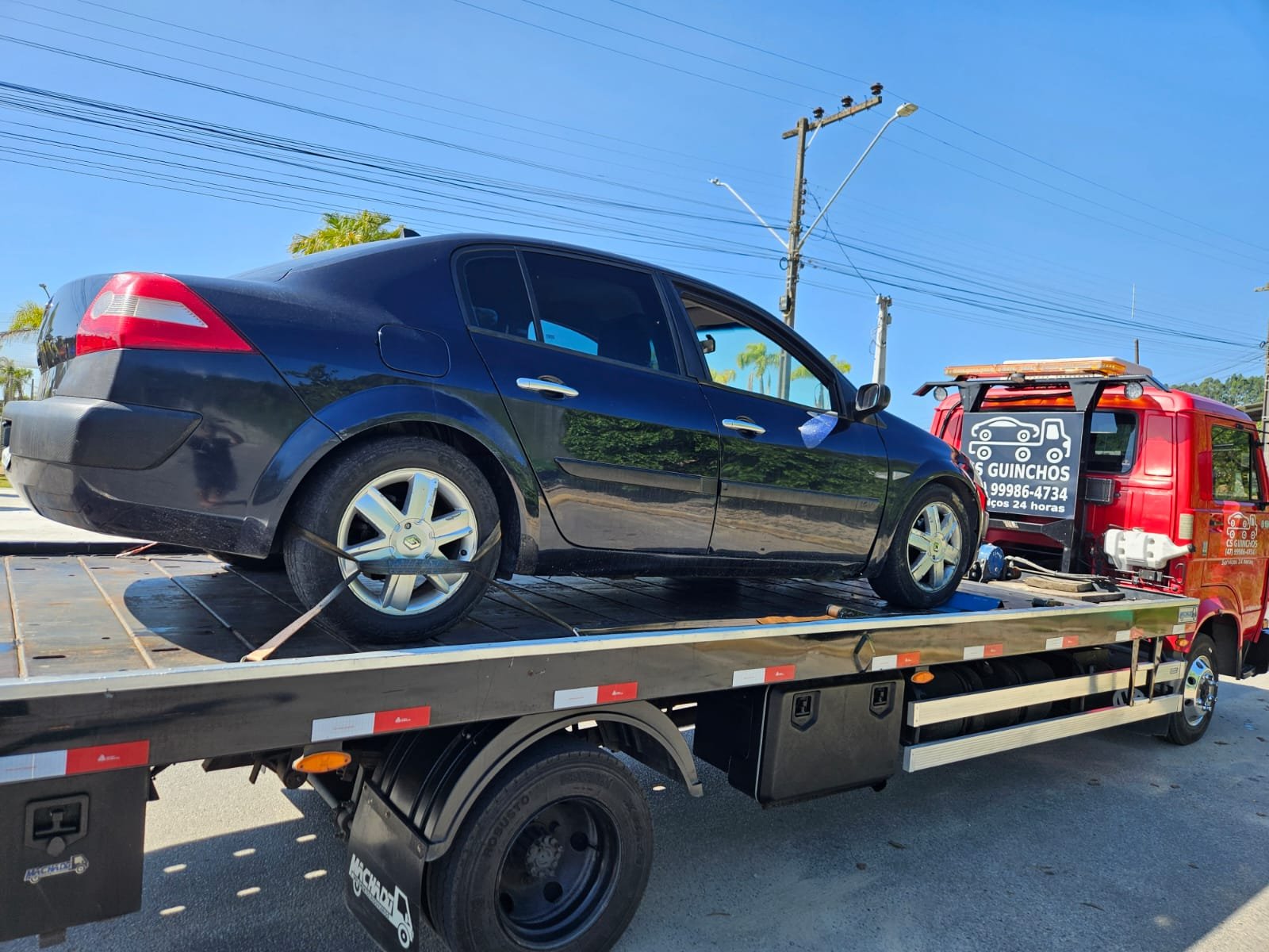 Sedã preto sendo rebocado na plataforma da CS Transportadora